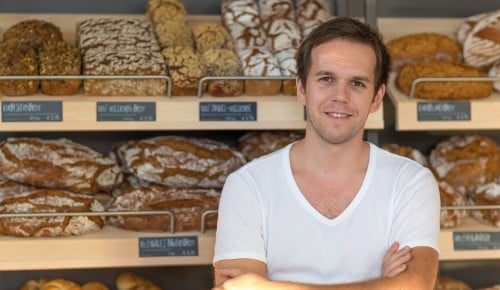 Andreas Riederich vor einem Holzregal mit Brot und Gebäck