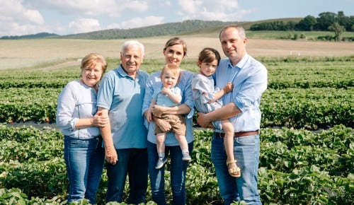 Familie Strohmaier in drei Generationen stehend in einem Erdbeerfeld an einem sonnigen Tag