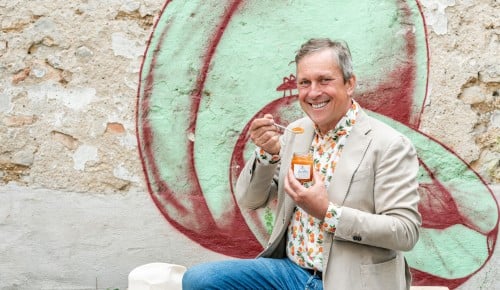 Stefan Schauer von der Firma Stauds sitzt auf einem Stapel Paletten und hält eine Marillenmarmelade in der Hand