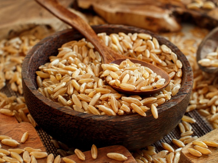 Raw Kamut grain in a wooden bowl with a spoon