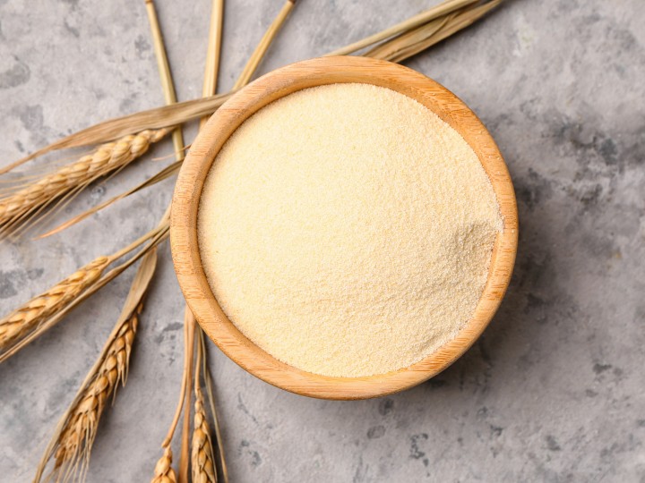 Bowl with raw semolina on grunge background