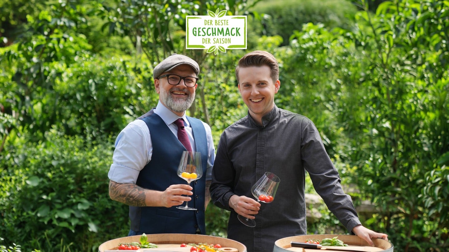 Hier sieht man zwei Sommeliers die sich gegenseitig zuprosten und die Cheryy-Tomaten in den Weingläsern betrachten