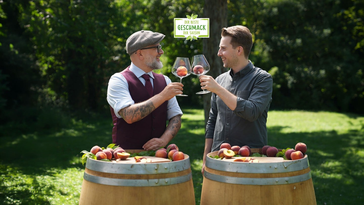 Hier sieht man zwei Sommeliers die sich gegenseitig zuprosten und die Nektarinen in den Weingläsern betrachten