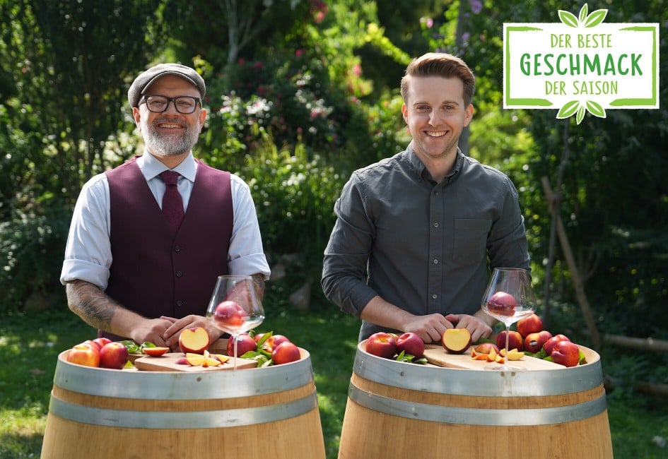 Hier sieht man zwei Sommeliers die sich gegenseitig zuprosten und die Nektarinen in den Weingläsern betrachten