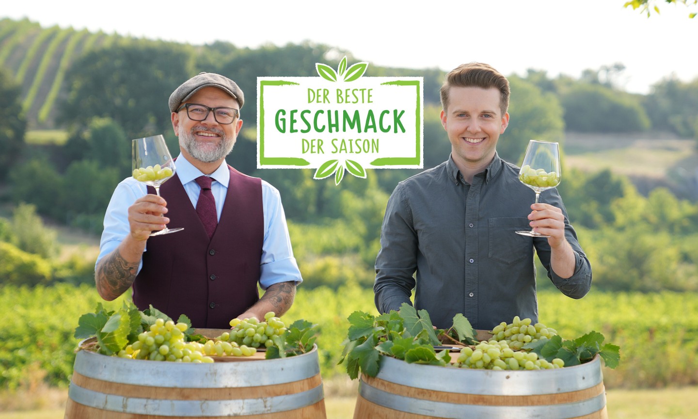 Hier sieht man zwei Sommeliers die sich gegenseitig zuprosten mit Trauben in den Gläsern