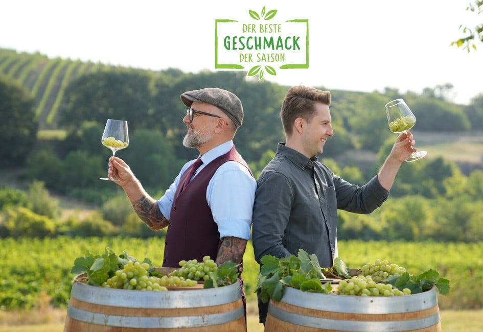 Hier sieht man zwei Sommeliers die sich gegenseitig zuprosten mit Trauben in den Gläsern