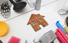 Holzhaus auf weißer Tischplatte mit Haushaltsgegenständen