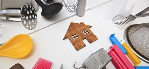Holzhaus auf weißer Tischplatte mit Haushaltsgegenständen