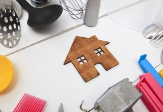 Holzhaus auf weißer Tischplatte mit Haushaltsgegenständen