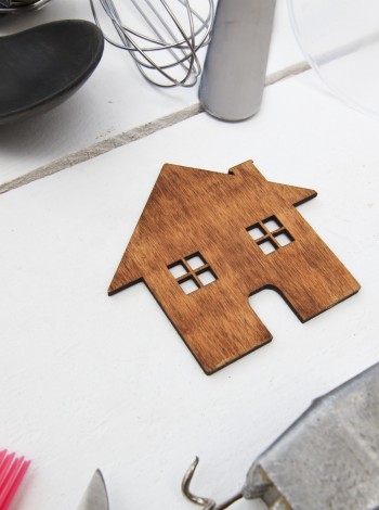 Holzhaus auf weißer Tischplatte mit Haushaltsgegenständen