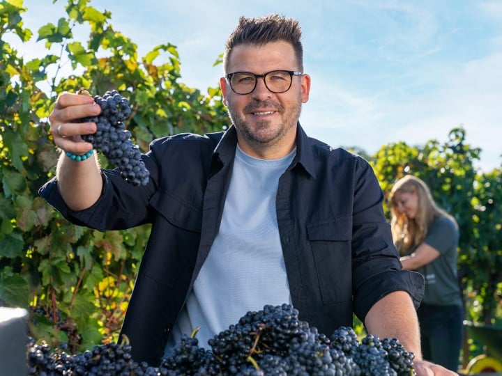 Weinbauer Hannes Reeh mit Trauben im Traubenfeld