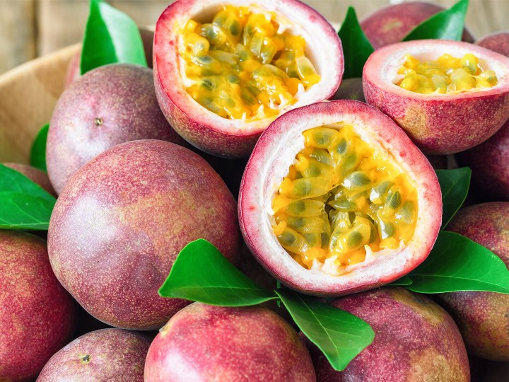 Nahaufnahme von frischer Passionsfrucht in einer Holzschale auf einem Holztisch in Seitenansicht mit Freiraum für Hintergrund oder Wallpaper. Reife Passionsfrucht, so köstlich süß und sauer.