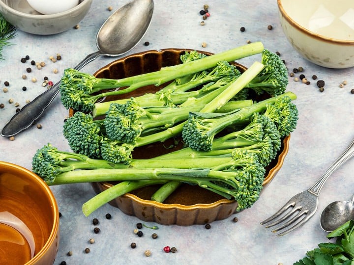 Roher Broccolini, vorbereitet auf einer sauberen Küchenfläche mit Gewürzen