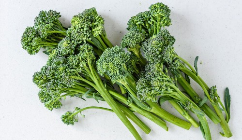 Organischer roher Broccolini auf einem weißen Schneidebrett