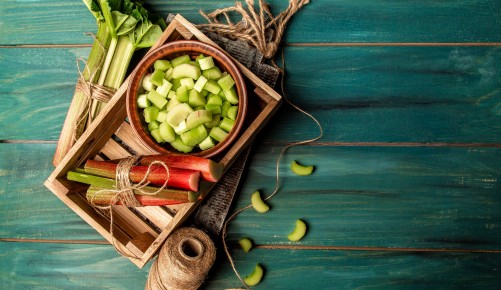 Rhubarb stalks on a board, Rhubarb in bowl on a wooden background. Rhubarb stalks on a board, Rhubarb in bowl on a wooden background. top view.