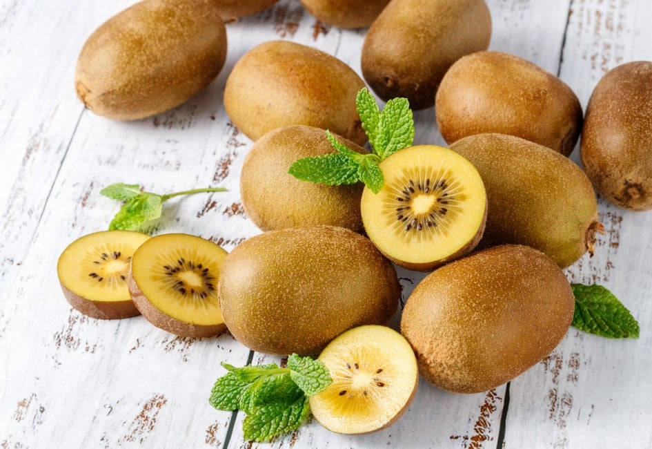 Fresh kiwi gold  fruits with mint leaves scattered  on rustic wooden table