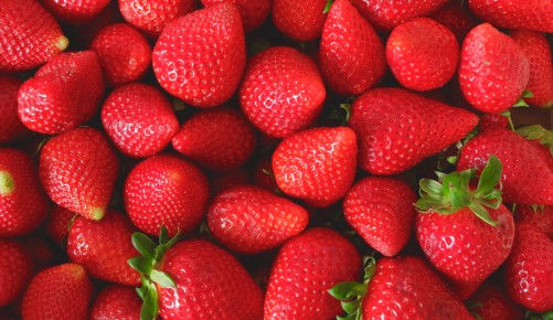 Many strawberries of faded red colour and different sizes on the local farmer market in Spain