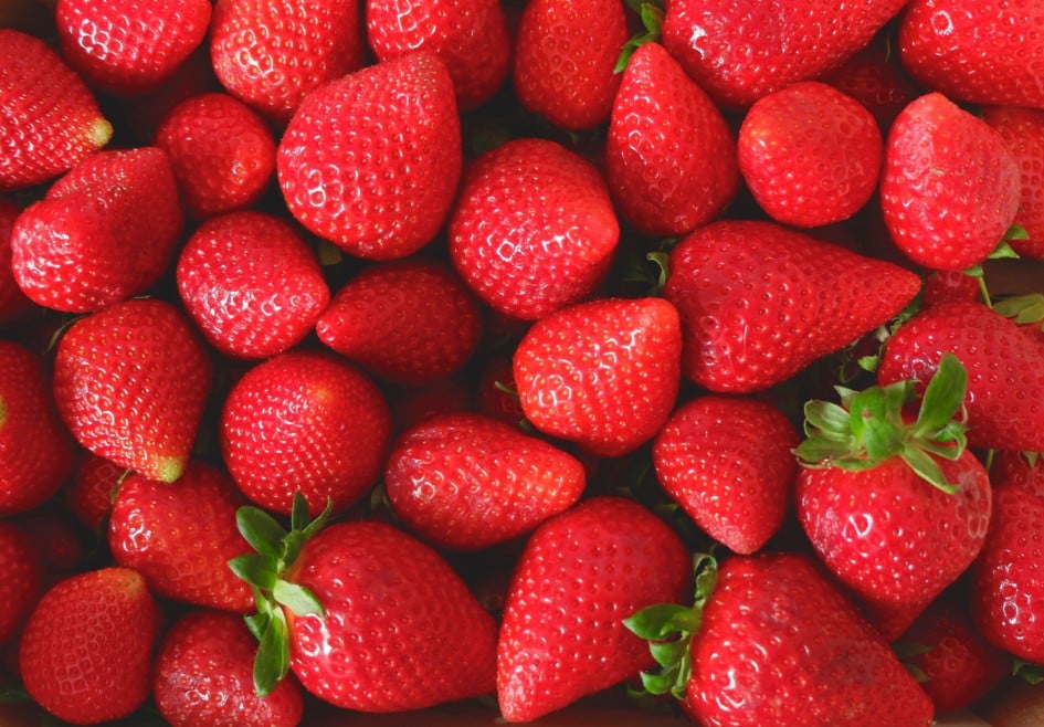 Many strawberries of faded red colour and different sizes on the local farmer market in Spain