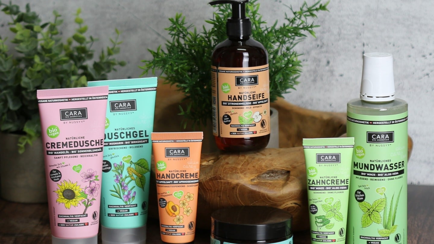 Cara by Nussyy Naturkosmetik, Produkte auf Holzplatte mit Pflanzen dekoriert