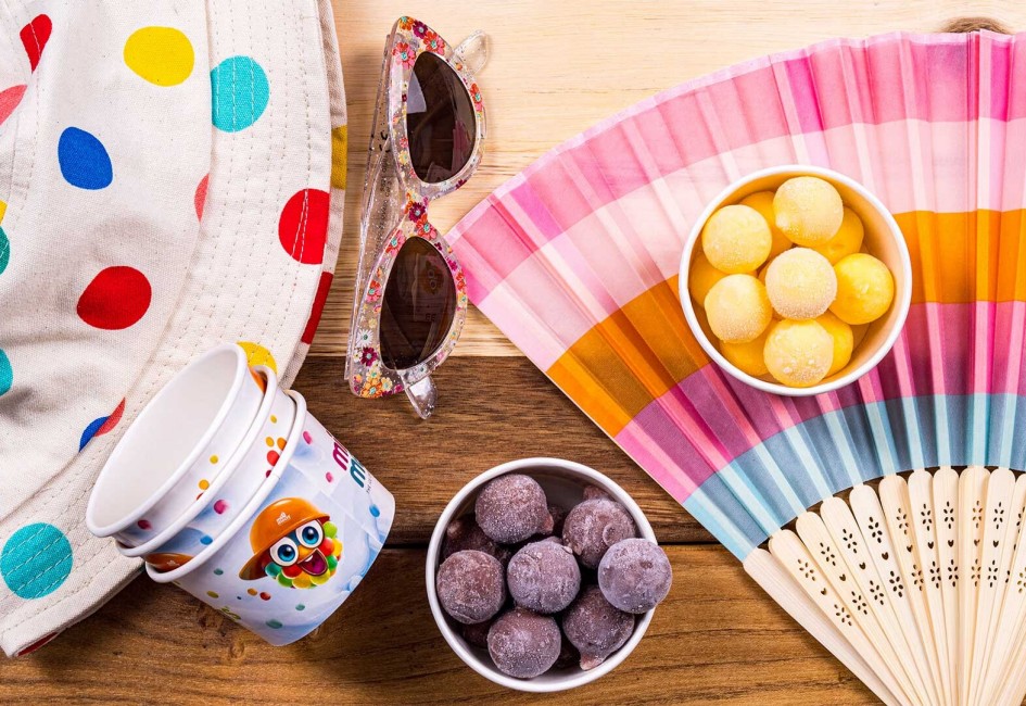 minimelts Kugeln im Becher in 2 Sorten, auf Sommerhintergrund mit Hut, Fächer und Sonnenbrille