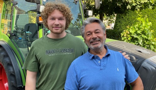 Valentin und Richard Zahel vor einem grünem Traktor, draußen