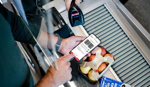 ein Mann an der Kasse scannt seinen App-Code an der Kassa